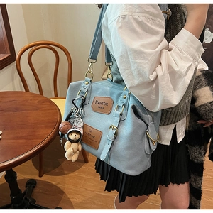 Detail of light blue lychee pattern faux leather bag with bear and basketball charms
