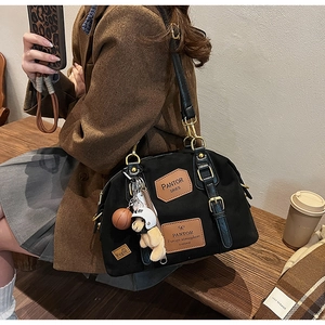Detail of black denim handbag featuring leather tags and creative charms in cozy setting