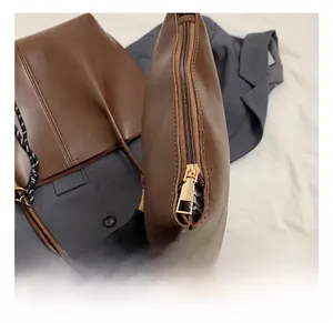 Close-up of golden metal zipper hardware on dark brown leather shoulder bag detail