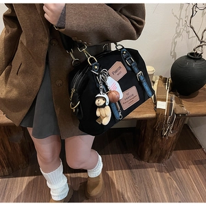 Detail of black canvas tote bag with leather handles and cute teddy bear keychain charm