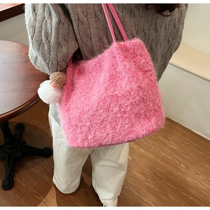 Détail de la texture peluche rose du sac cabas avec charm de poupée sur l'épaule