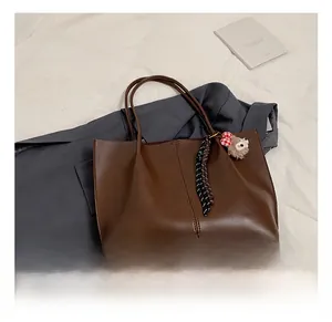 Brown leather tote bag featuring a cute plush bear and polka dot ribbon detail