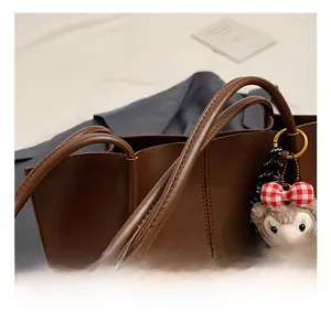 Detail showing comfortable reinforced round handle and glossy leather of the coffee tote bag