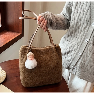 Sac fourre-tout en peluche marron avec anses en cuir et pendentif poupée sur table