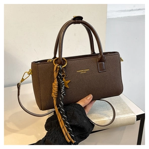 Detail of dark brown handbag showing gold star charm and woven rope decoration
