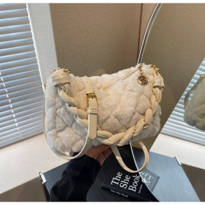 Détail du sac en peluche blanc avec matelassage, poignée tressée et médaillon doré