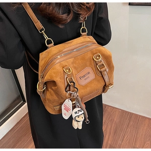 Close-up of brown suede multi-way backpack with vintage logo and bear charm detail