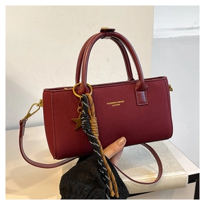 Detailed macro view of burgundy vintage handbag with star charm and woven tassels
