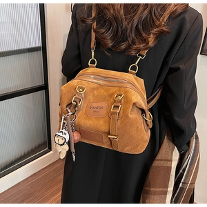 Detail view of brown suede backpack with PANTOR SRIES logo and cute bear charm accent