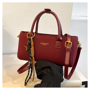 Close-up of wine red crossbody bag with leather handle and fashion gold lettering