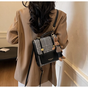 Detail of houndstooth shoulder bag with black trim and plush rabbit keychain