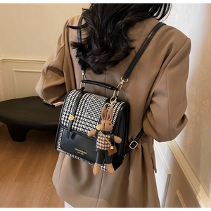 Detail of houndstooth mini backpack with cute bunny charm and golden metal hardware