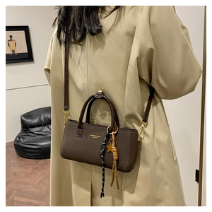 Brown leather crossbody bag with star charm shown on model in a beige coat