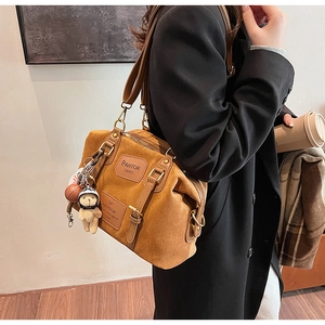 Detail of caramel brown Boston bag worn crossbody with cute bear and basketball charms