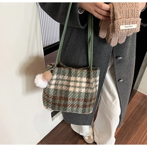 Détail du sac cabas en laine à carreaux avec bandoulière verte et breloque pelucheuse