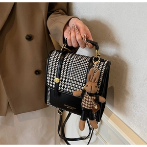 Close-up of houndstooth crossbody bag with leather trim and cute rabbit charm