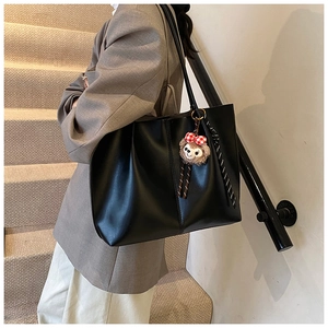 Modern black PU leather tote bag with red plaid bow plush charm shown on a model