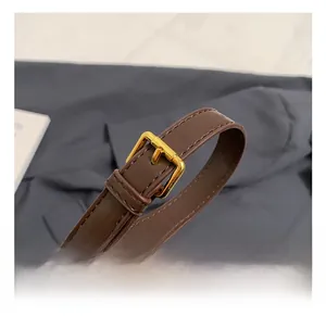 Detail of adjustable dark brown leather shoulder strap with gold metal buckle and stitching