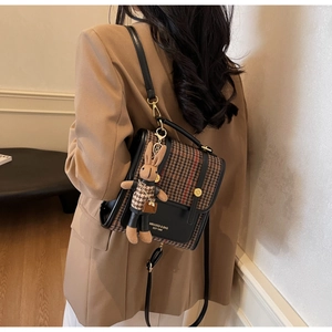 Detail of color-block houndstooth backpack with flap closure and rabbit charm accessory