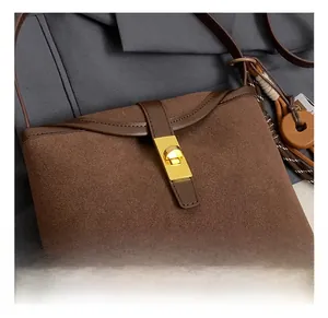 Close-up of vintage brown suede and leather crossbody bag with golden rotating metal lock