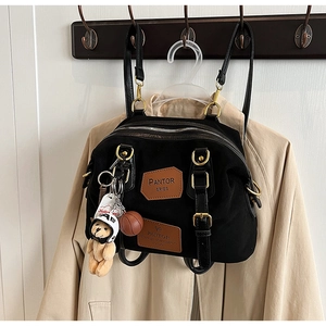 Detail view of black denim backpack with leather patches and cute bear charm pendant