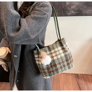 Détail du sac seau à carreaux en laine avec charm de poupée en peluche et bandoulière