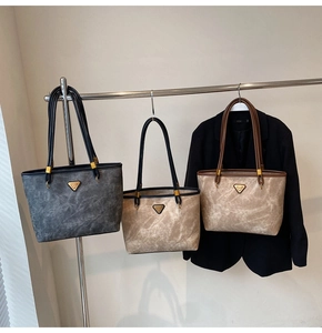 Detailed view of tote bags with marble texture and signature triangular metal buckle