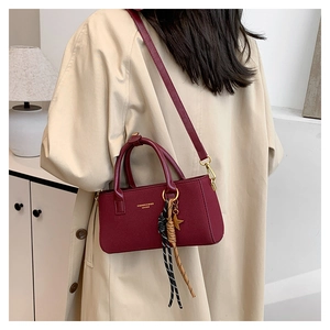 Detail of burgundy leather handbag with golden star charm and colorful tassels