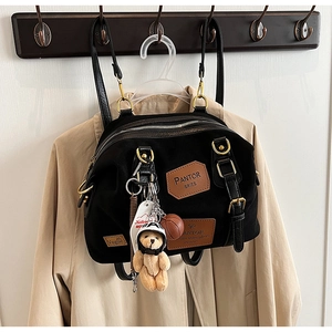Detail of multi-functional black canvas backpack with vintage patches and teddy bear charm