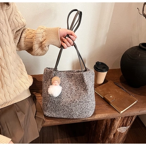 Détail d'un sac cabas en tricot gris avec anse en cuir noir et breloque peluche