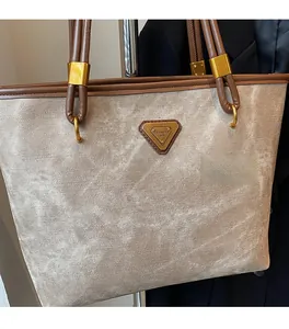 Close-up of beige textured tote bag with brown leather handles and golden metal hardware