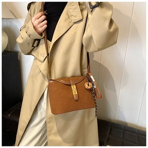 Close-up of brown matte suede crossbody bucket bag with golden buckle and woven charm