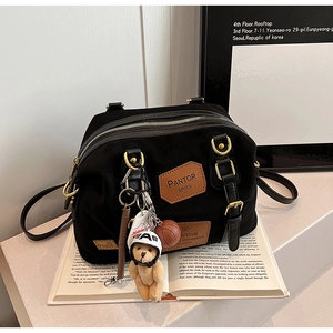 Close-up of black denim Boston bag with leather handles and decorative bear charms