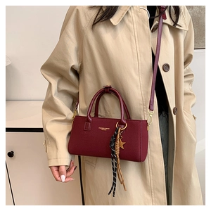 Detail showing vintage burgundy leather bag with gold hardware and woven star charm strap