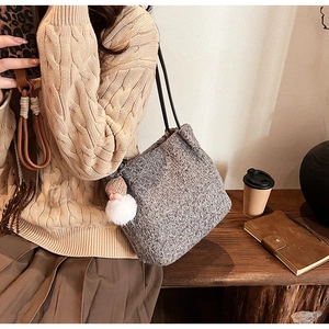 Détail de la texture en maille du sac gris avec pendentif peluche dans un cadre chaleureux