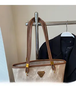 Detail of vintage tote bag with light fabric texture, brown leather trim and metal triangle logo