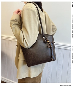 Detail of dark brown tote bag with decorative woven knots and golden metal ball charms