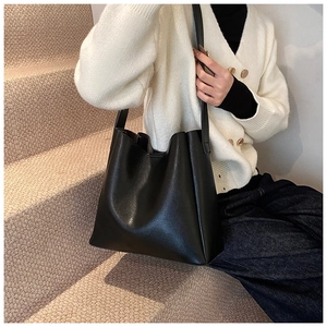 Detail shot of a large black leather hobo bag on a model in a minimalist setting
