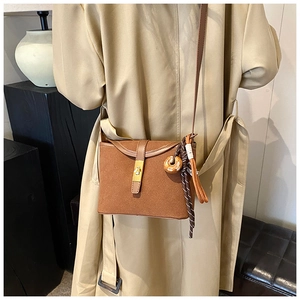 Detail of a brown matte suede crossbody bag featuring a golden square twist lock