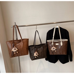 Close-up of three faux leather tote bags with animal texture and sheep charms
