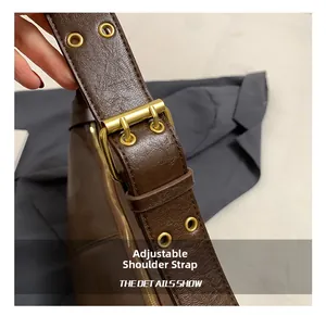 Close-up of adjustable strap on brown lychee leather bag with gold hardware