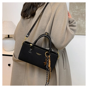 Close-up of black leather handbag with gold star charm and woven rope decoration