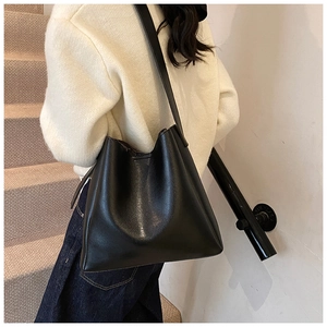 Detailed view of the black faux leather tote bag worn by a model in a casual setting