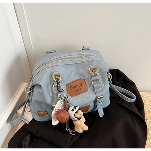 Detailed close-up of light blue denim texture bag with vintage bear and basketball charms