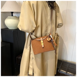 Detail of a brown matte bucket bag with gold square lock and elegant tassel charm