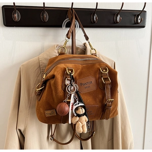 Detail of brown suede backpack with PANTOR SERIES badge, teddy bear and basketball charms