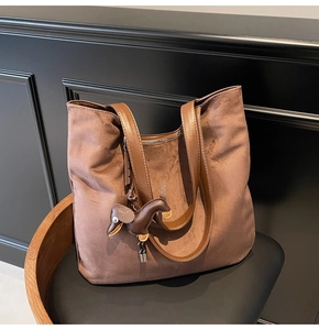 Détail d'un sac cabas en suédine marron avec anses en cuir et pendentif teckel
