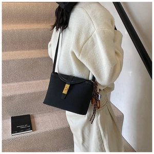 Detail of black matte crossbody bag featuring gold twist lock and printed silk scarf