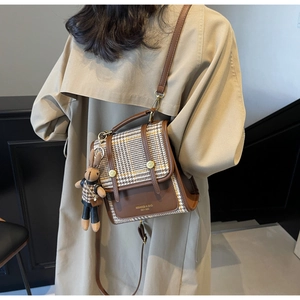 Detail of a brown leather shoulder bag with houndstooth flap and cute rabbit charm