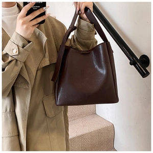 Detail of soft matte leather texture and wide strap on dark brown bucket tote bag